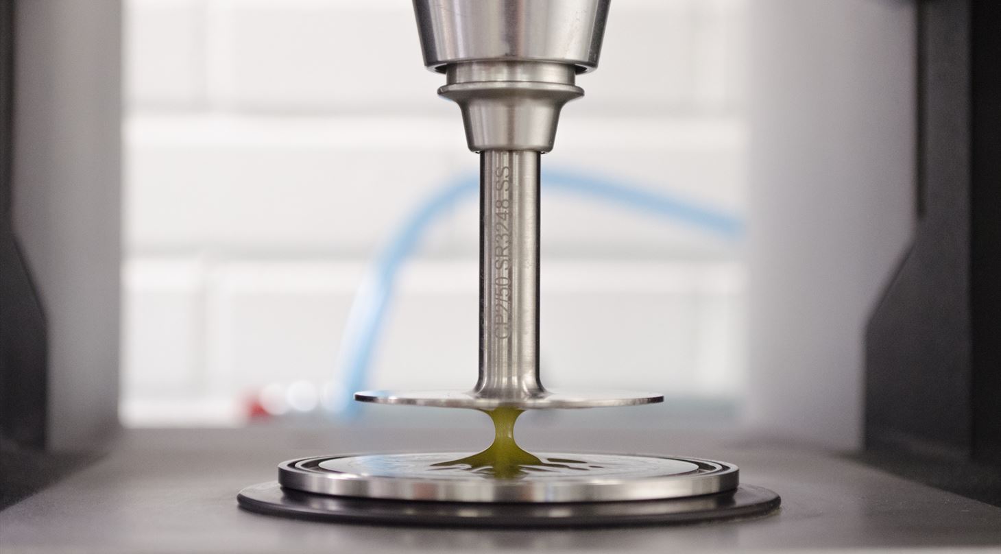 Et udstyr der måler reologiske egenskaber i en gul væske mellem to metalplader