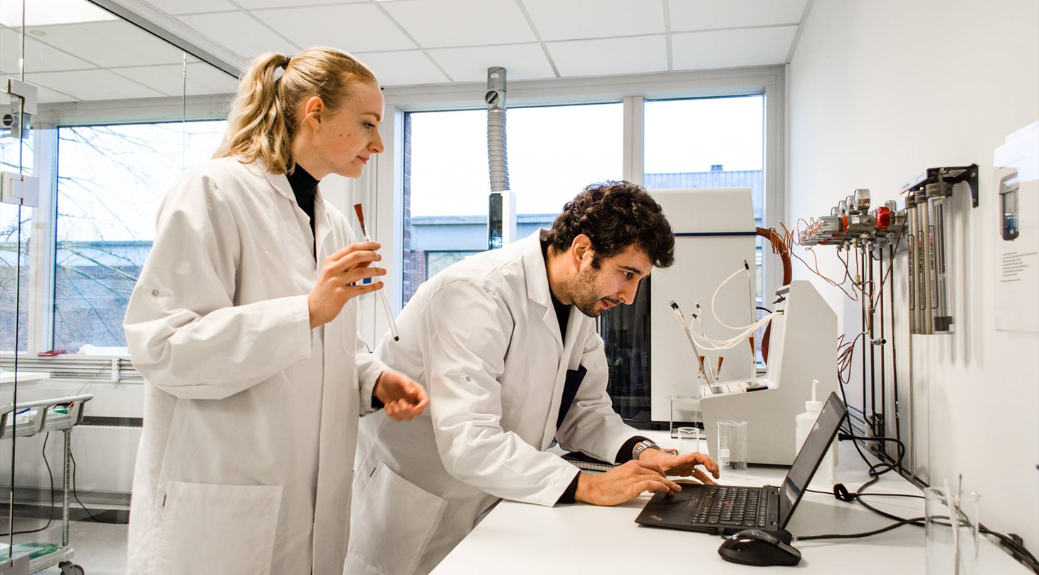 Men and Women looking to a PC in white labcoats.