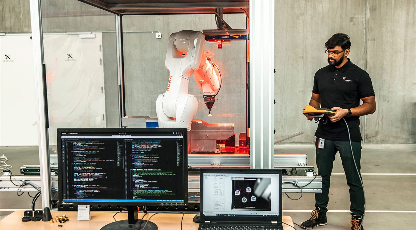 Ansat ved Teknologisk Institut programmerer en robot, som gør brug af AI