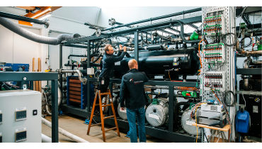 To medarbejdere str i HTHP Lab og justerer p en del af rrene