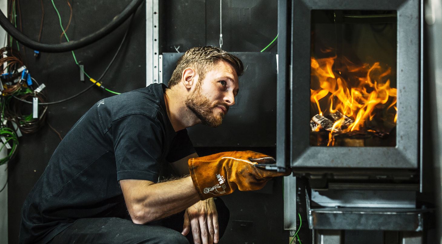 Man looking into wood stove to upgrade to EN 16510
