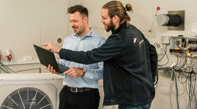 The picture shows two test engineers in the Heat Pump Test Laboratory at Danish Technological Institute
