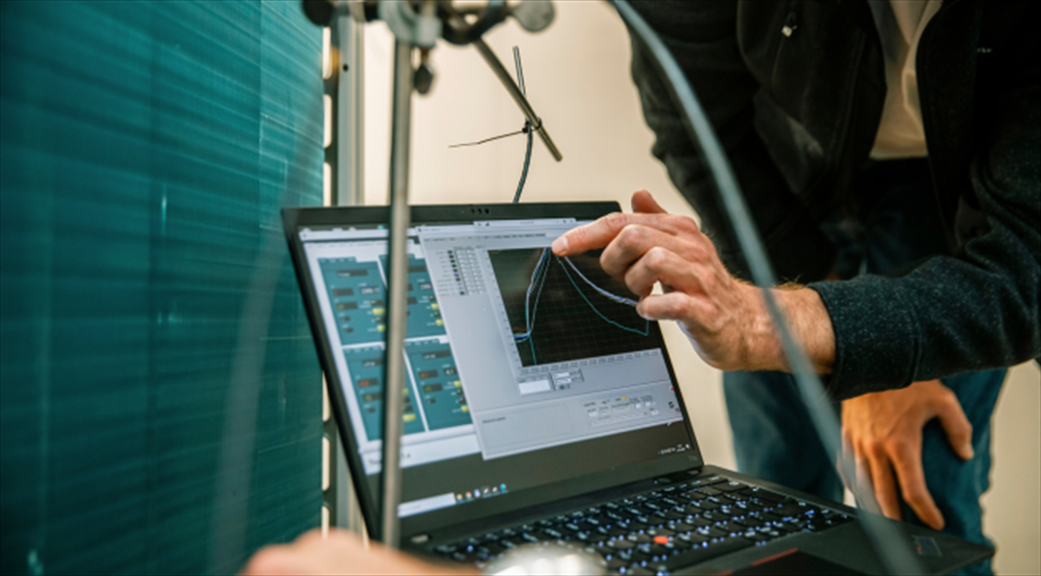 The picture shows a male hand pointing at a computer screen with test results